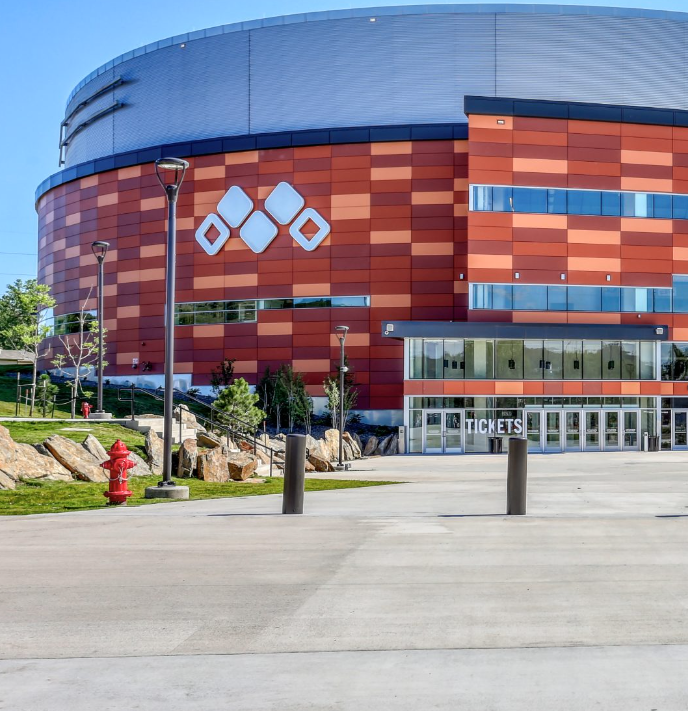 Arena exterior with red and orange siding, entrance doors, and