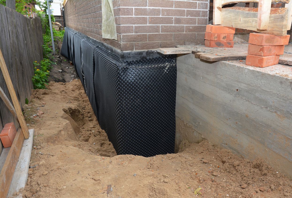 A drainage system is being installed on the side of a house.