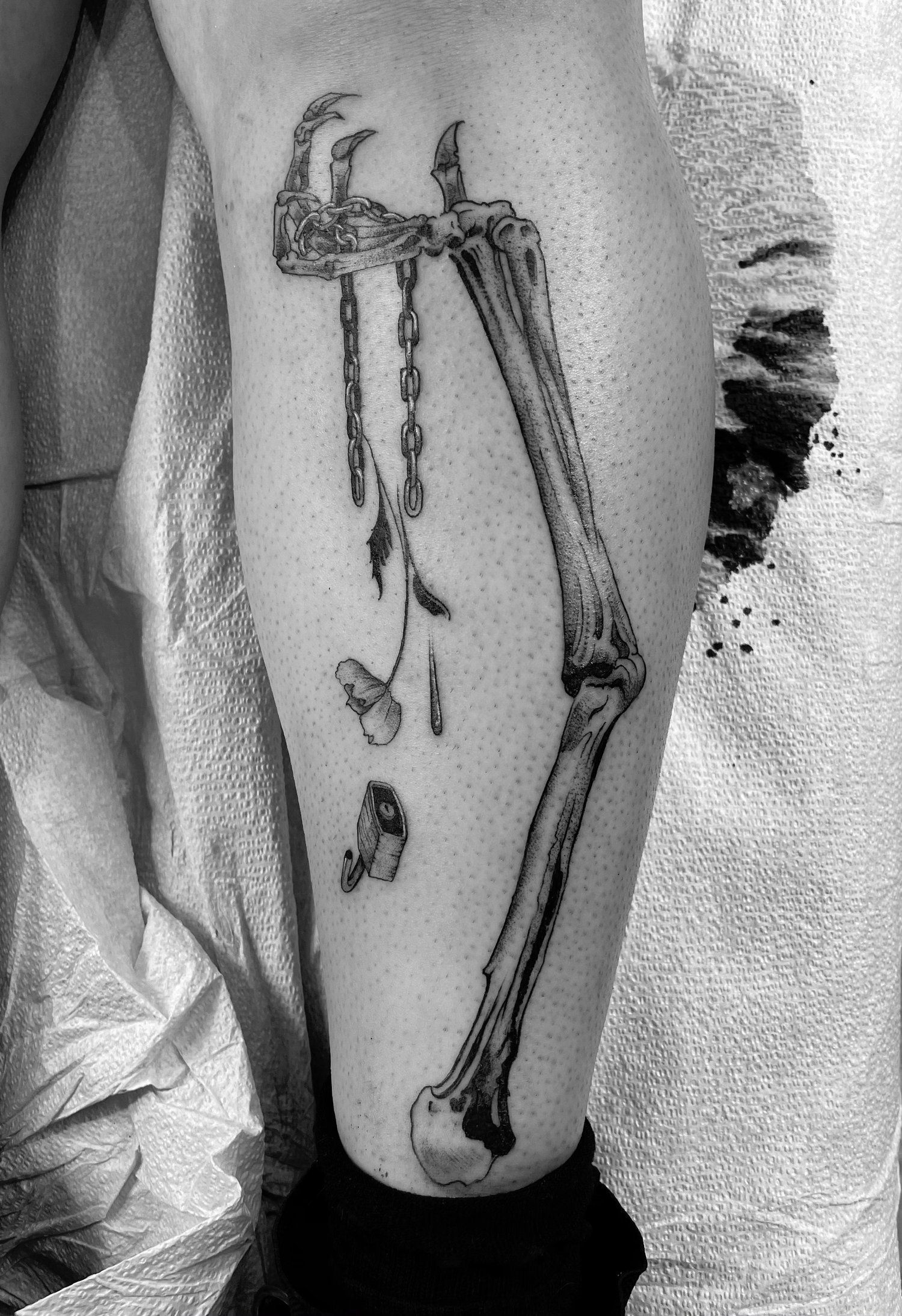 A black and white photo of a person 's leg with a skeleton tattoo on it.