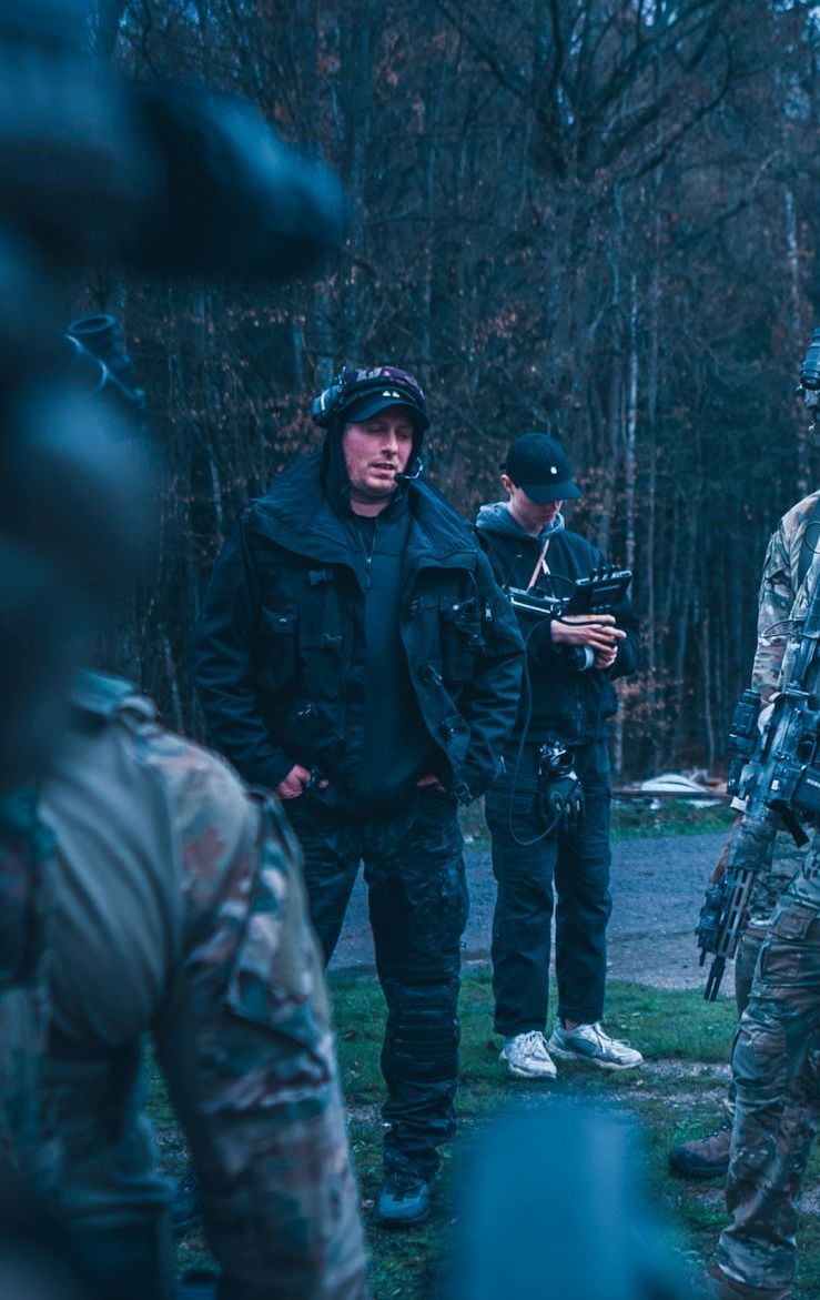 Ferdi Fischer dirige una scena di un film commerciale a sfondo tattico, affiancato da veri operatori militari sul set.