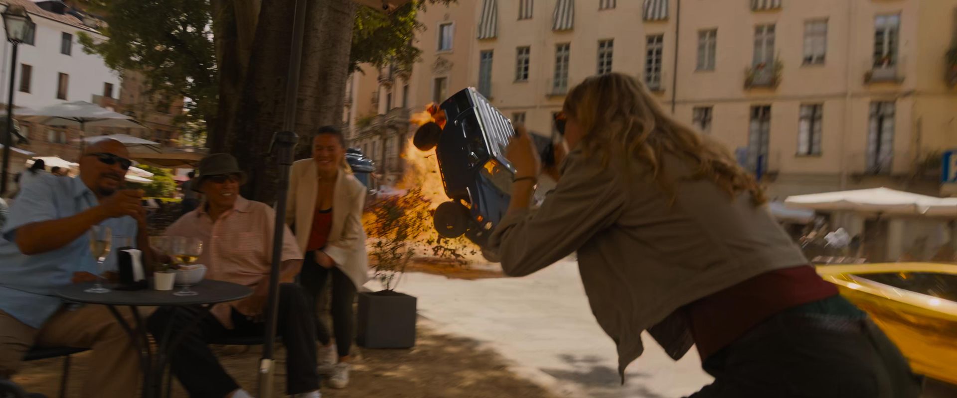 Fast X action scene in Rome with an explosion and a flipping car behind posing tourists.