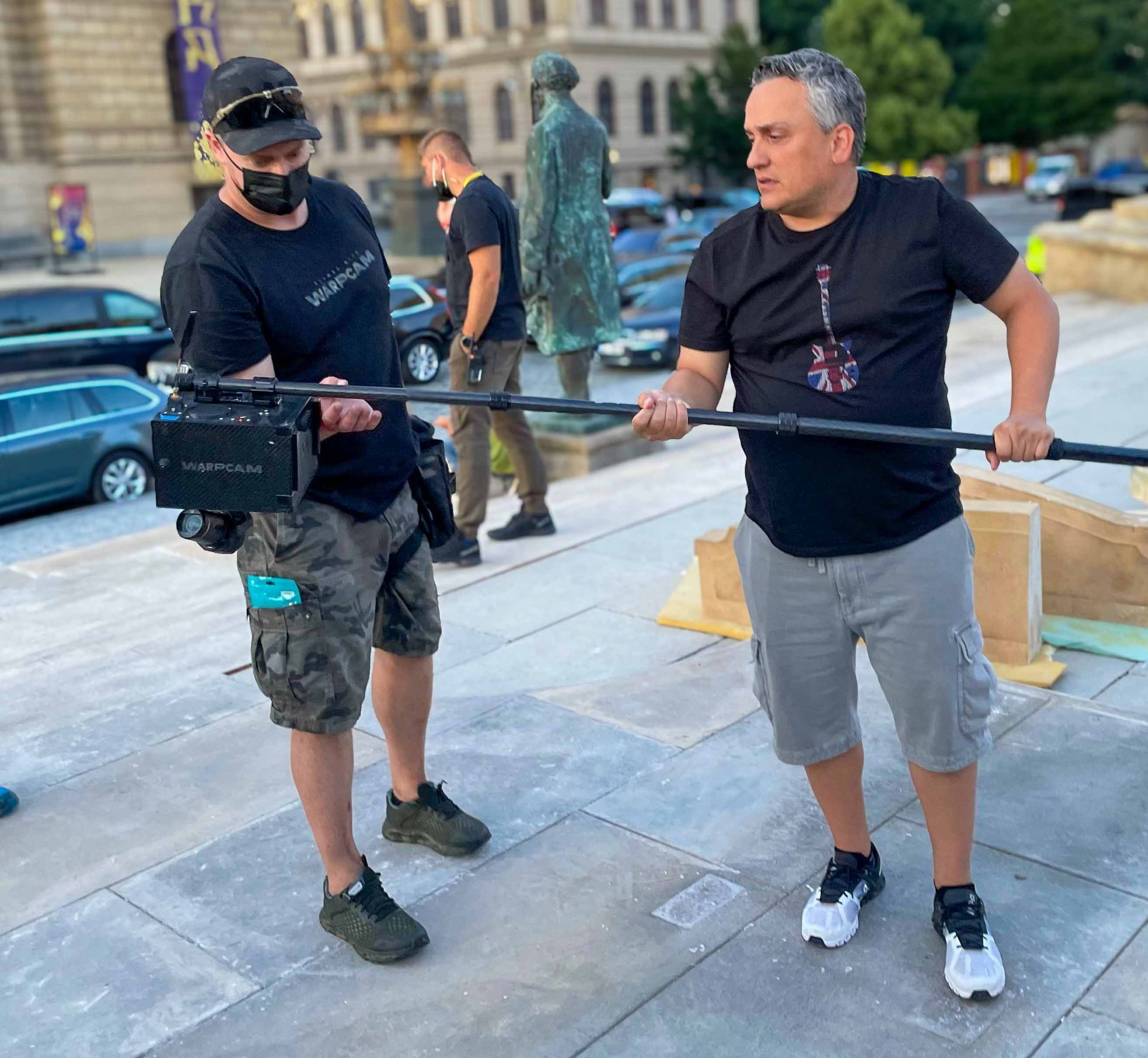 Ferdi Fischer standing close to Joe Russo, demonstrating how the WarpCam® pole prototype is operated on The Gray Man set in Prague.