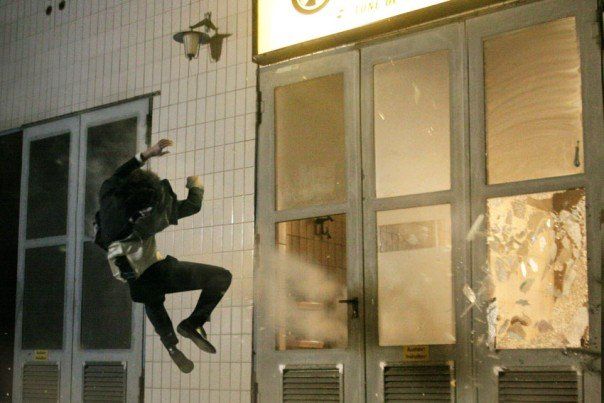 Ferdi Fischer pulled backward as an explosion shatters windows on a film set.