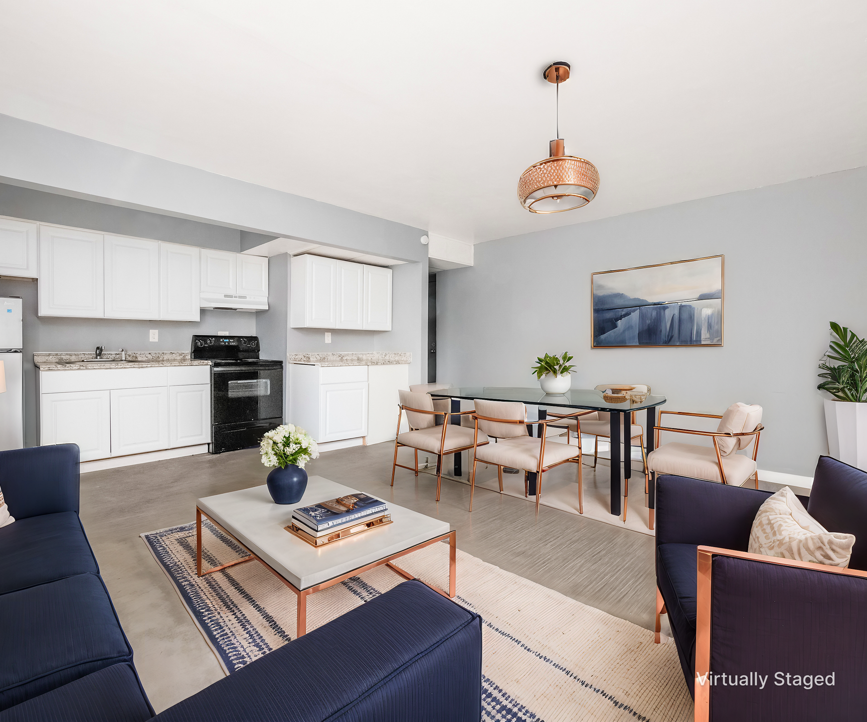Bright living-dining room with white kitchen, navy sofa, wooden table, and large window light