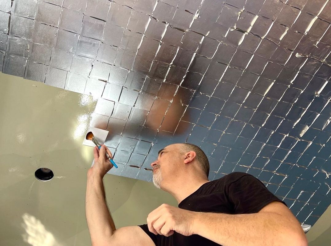 A man wearing glasses is standing in front of a gold ceiling