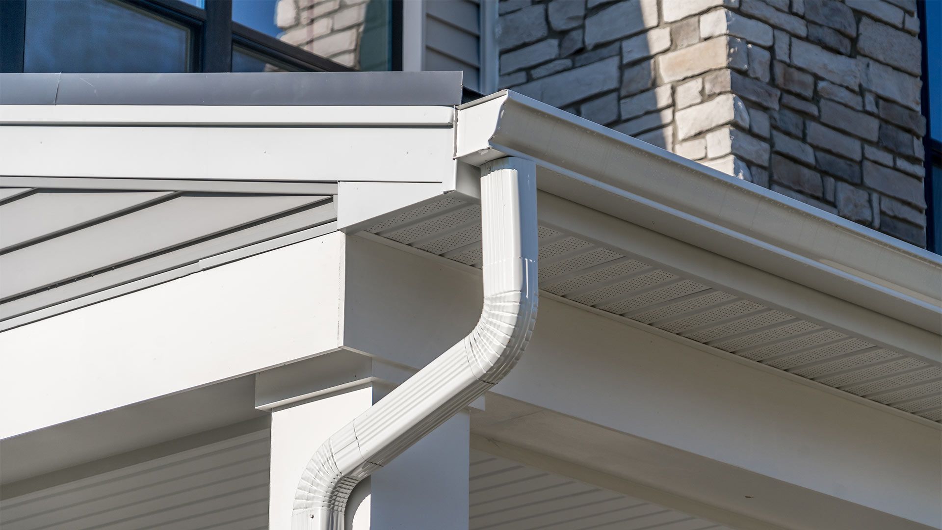 A close up of a white gutter on the side of a house.