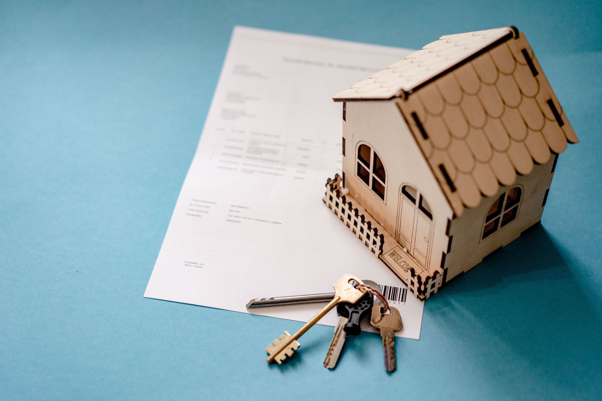 Miniature house with keys on a mortgage document against a blue background