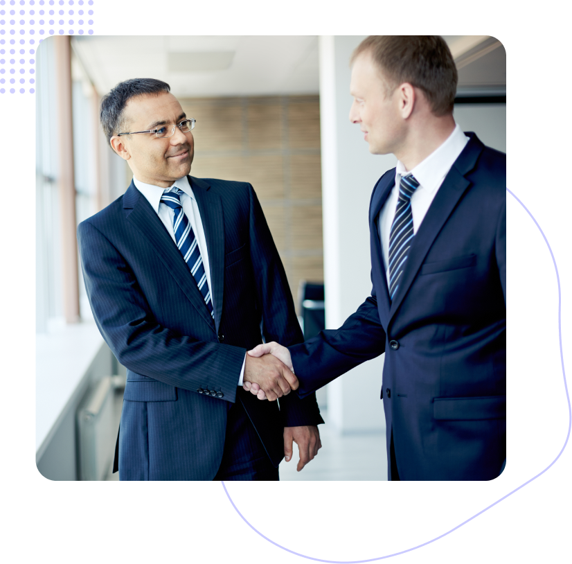 Two men in suits and ties are shaking hands in a hallway.