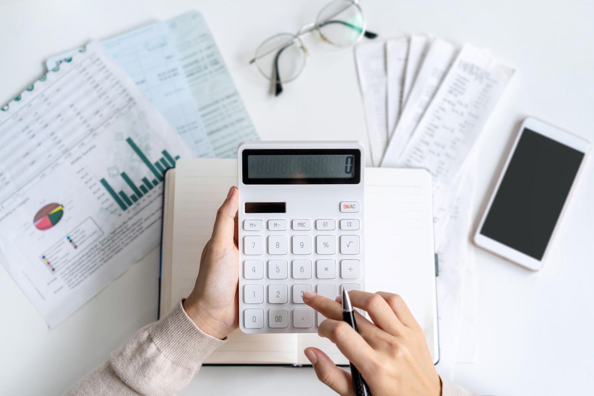 A person is using a calculator on a desk.