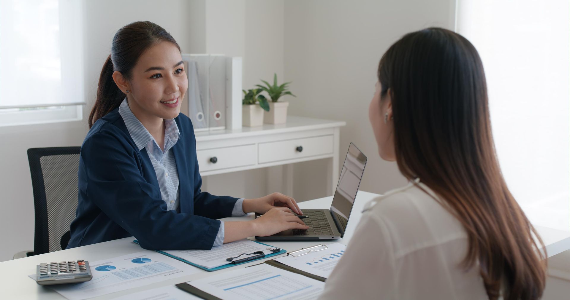 A woman is sitting at a table talking to another woman.