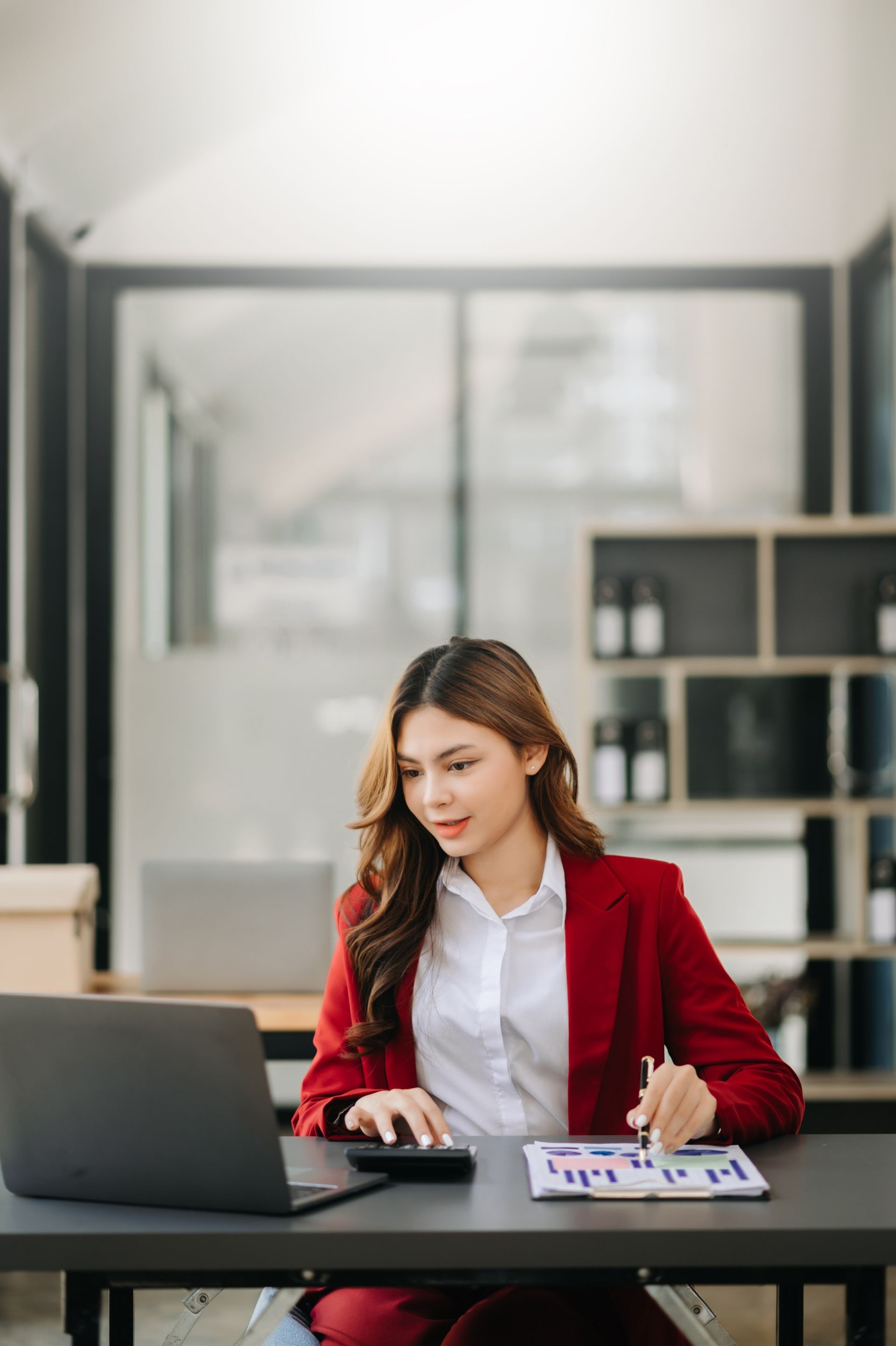 A woman is sitting at a desk using a laptop computer.