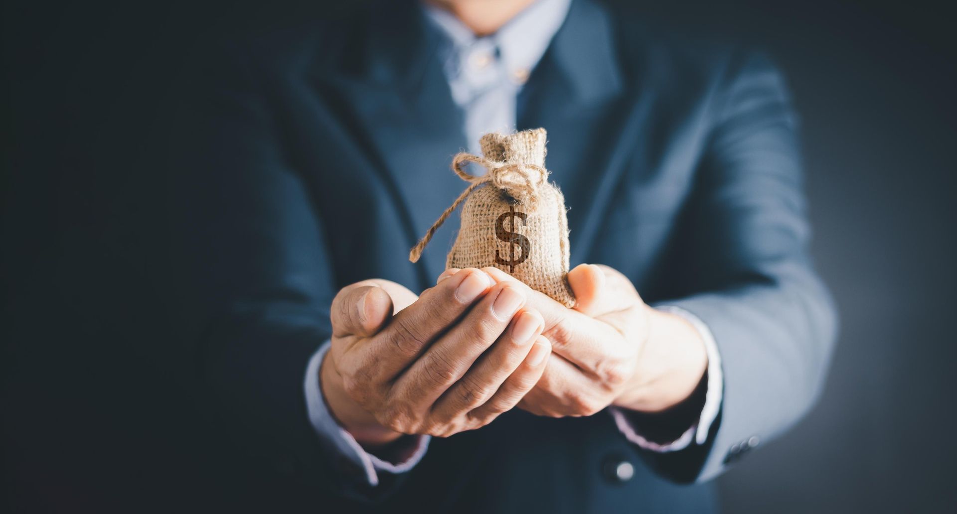 A man in a suit is holding a bag of money in his hands.