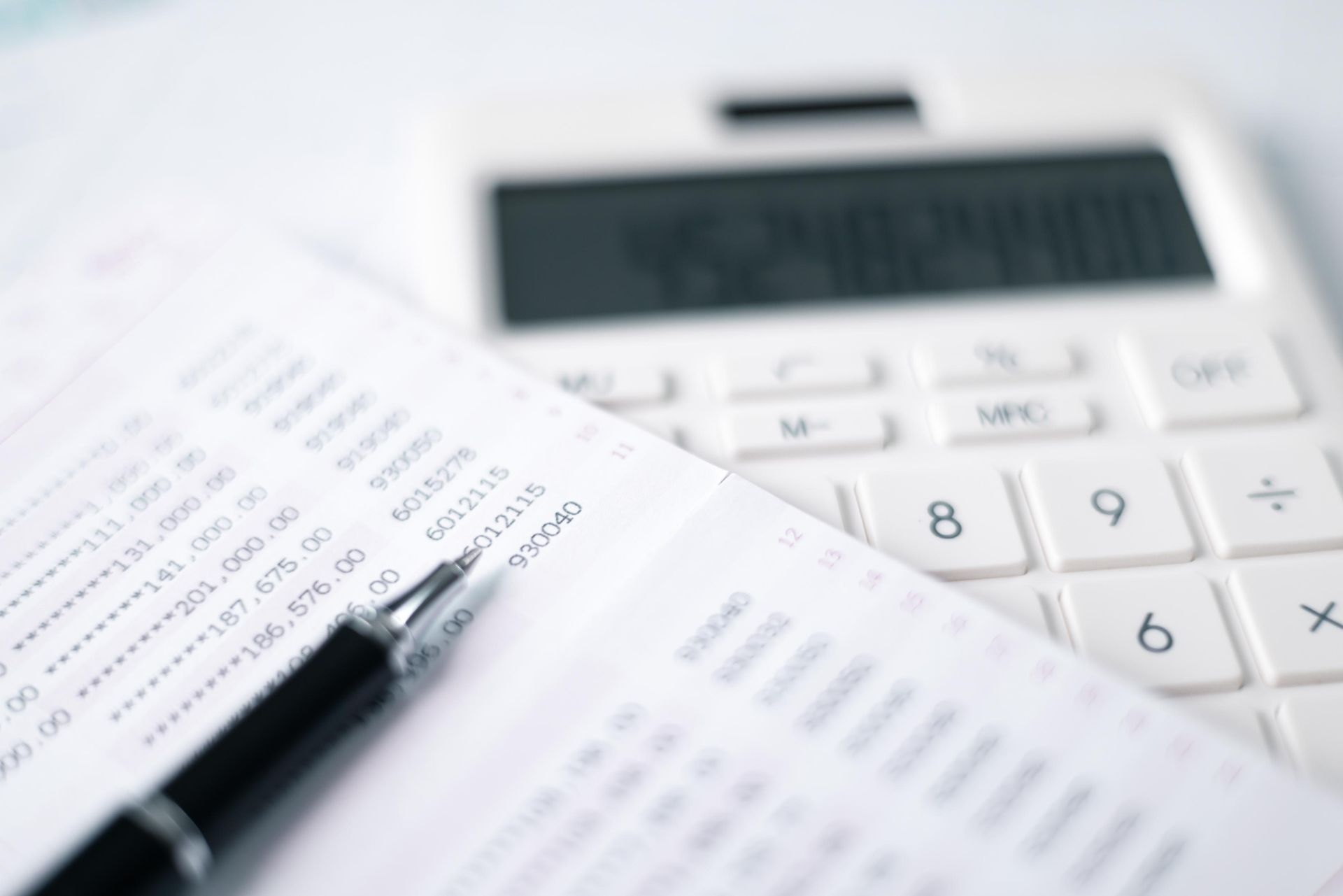 A pen is sitting on top of a piece of paper next to a calculator.