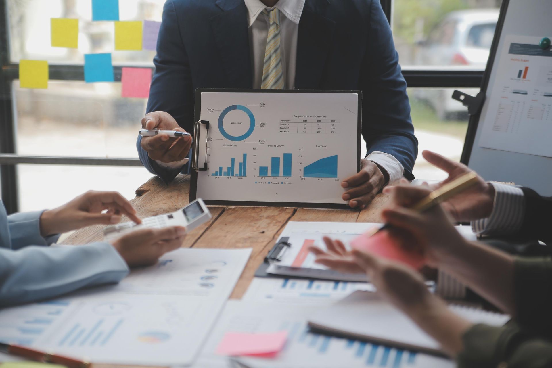 A man is sitting at a table holding a clipboard with a graph on it.