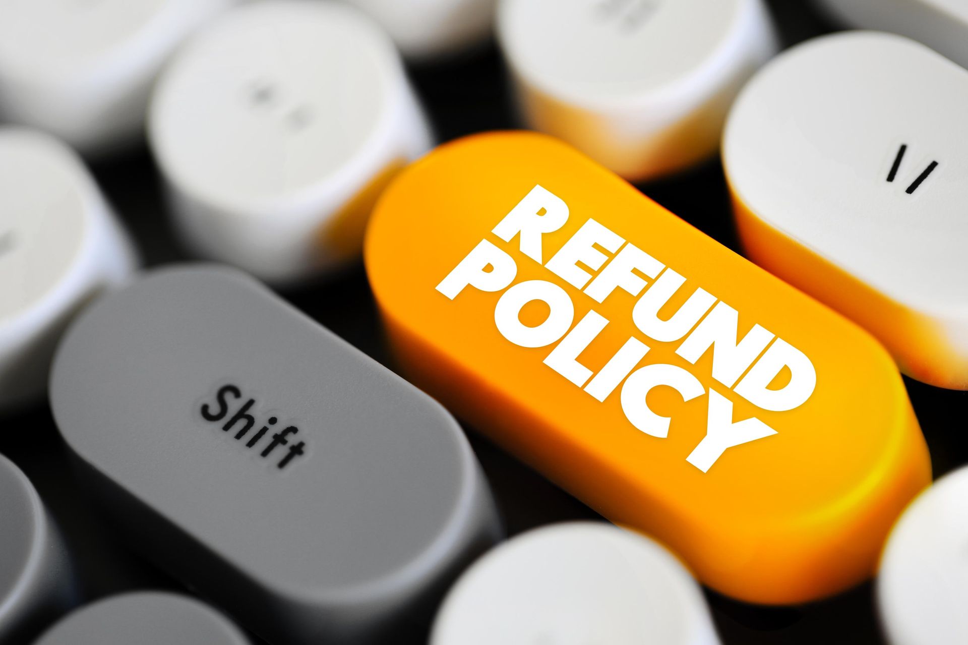 A yellow button on a keyboard that says refund policy.