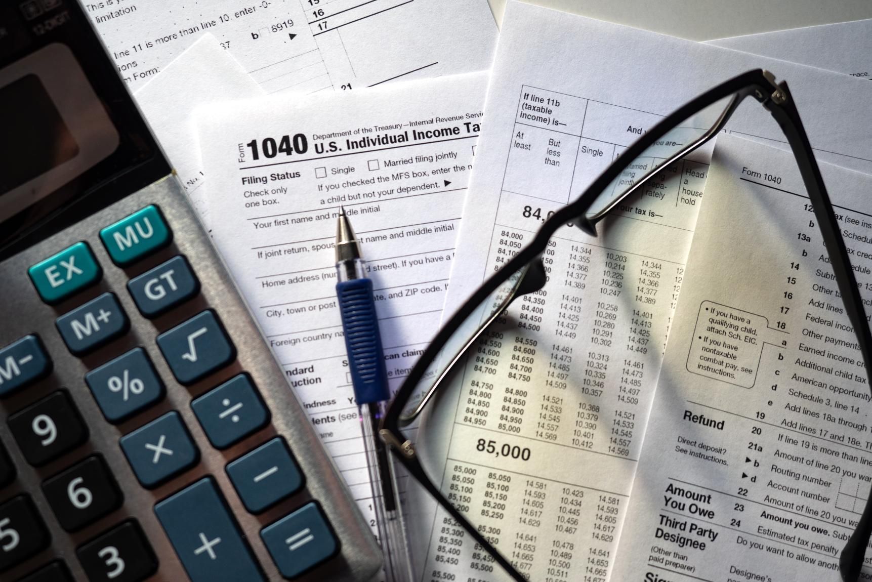 A calculator is sitting on top of a 1040 tax form.