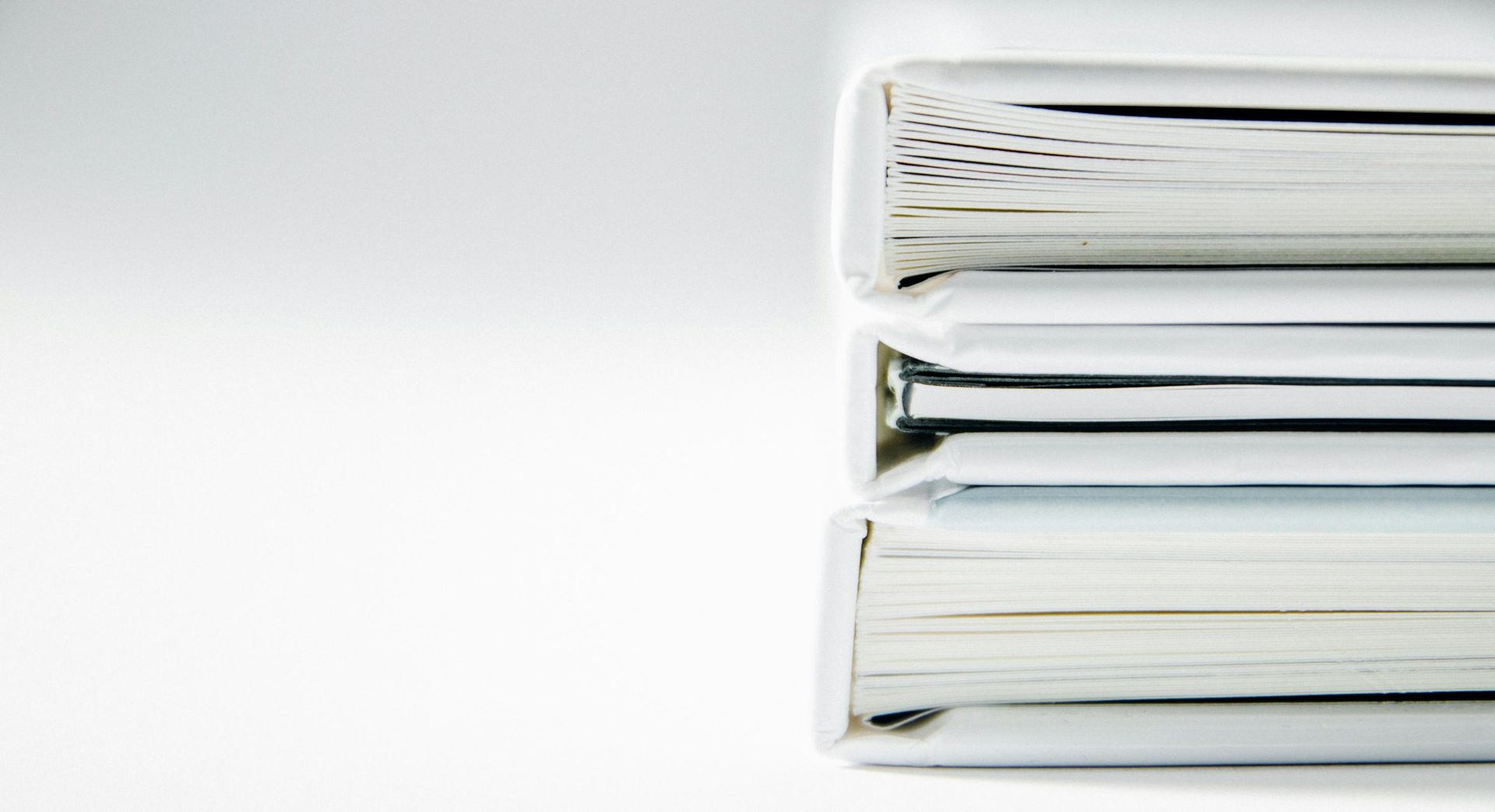 Three binders are stacked on top of each other on a white surface.