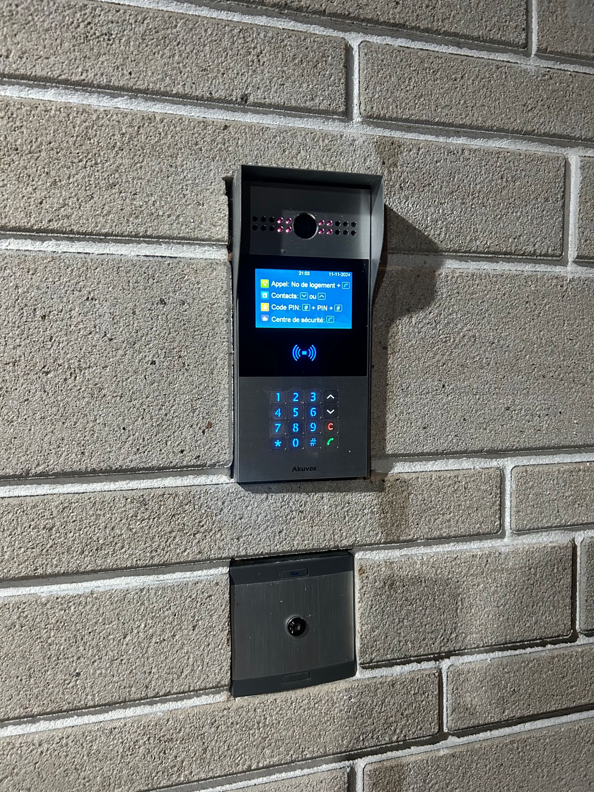 Une sonnette vidéo est montée sur un mur de briques.