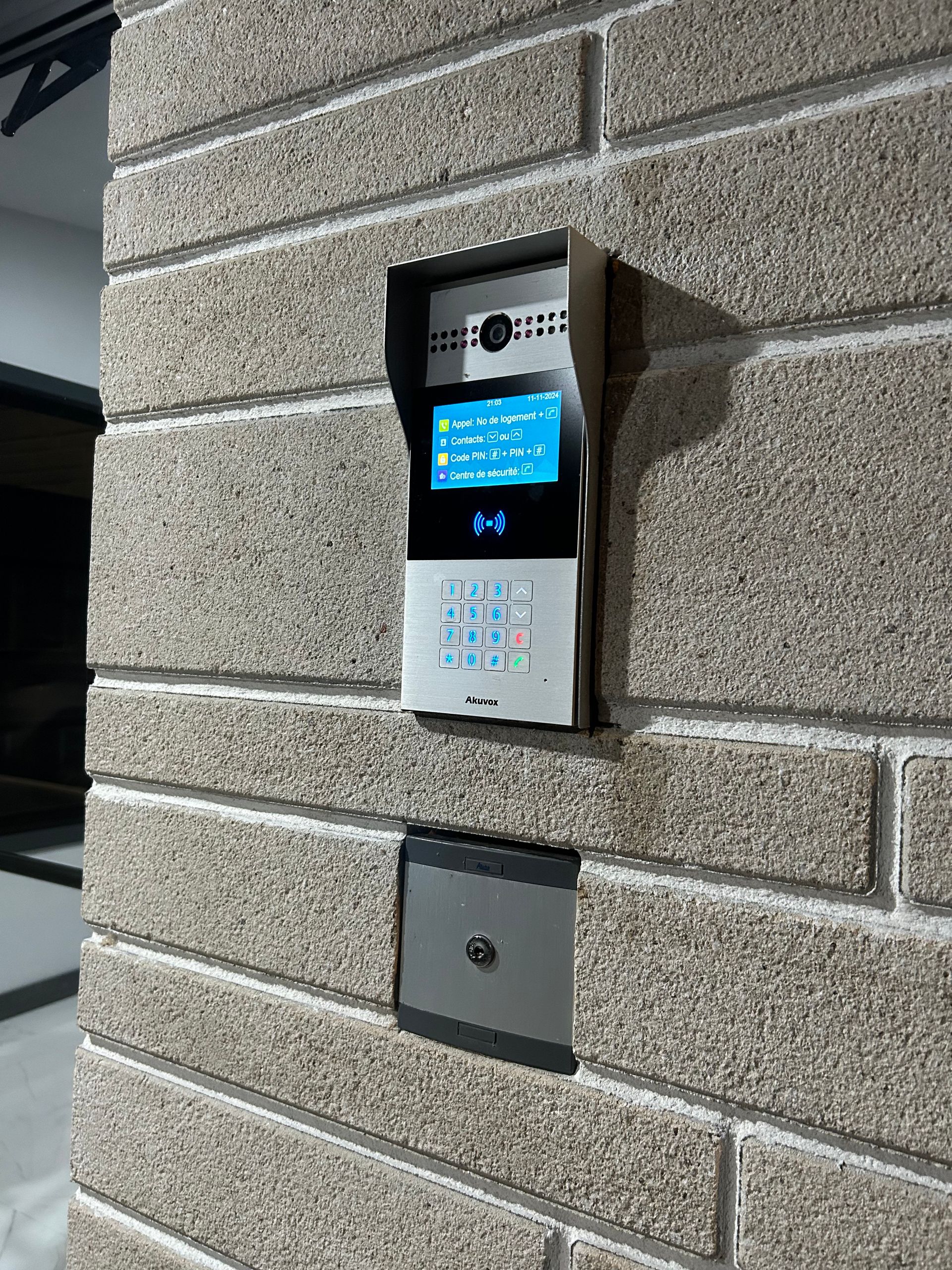 Une sonnette vidéo est montée sur un mur de briques.