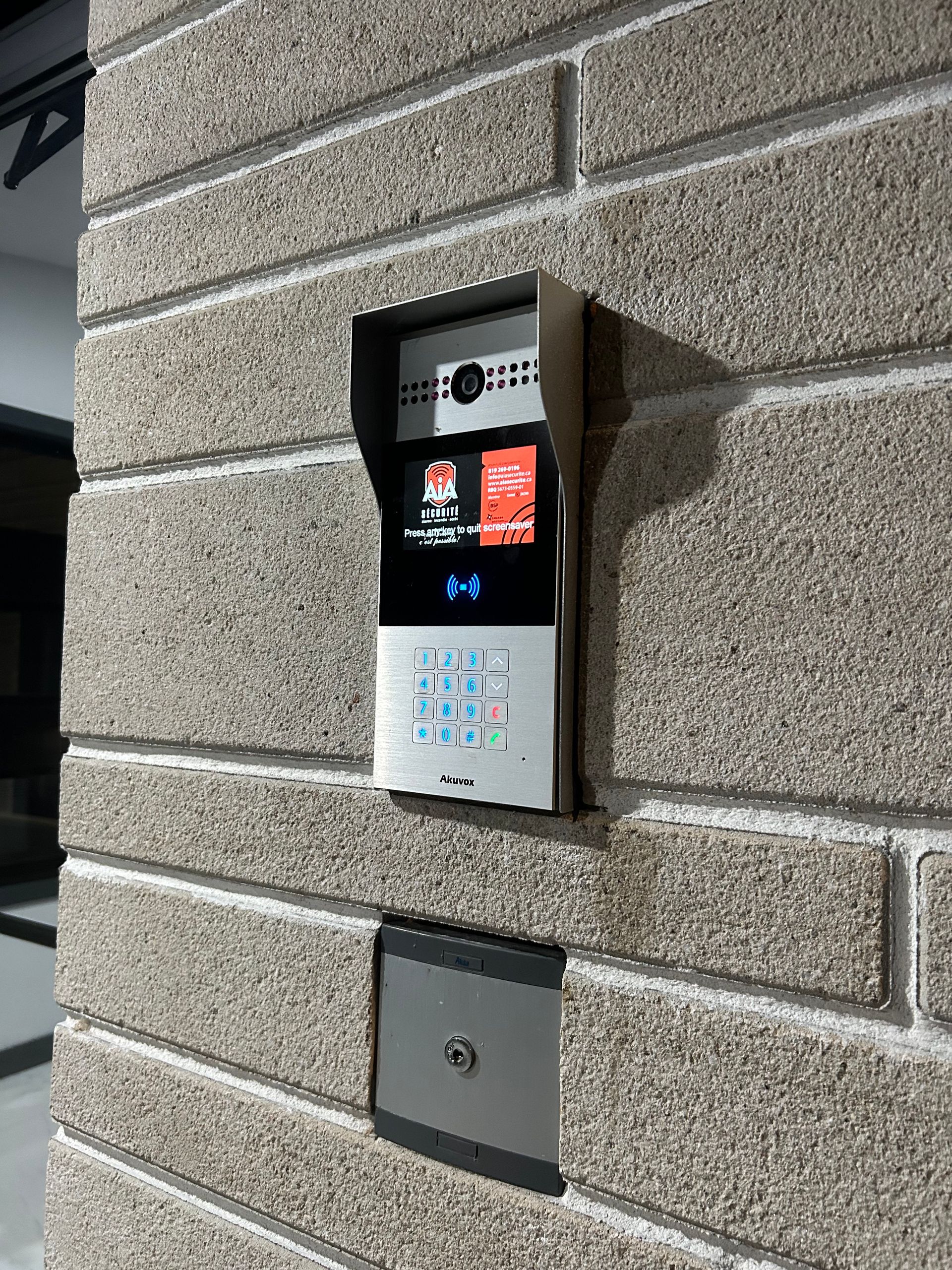Une sonnette vidéo est montée sur un mur de briques.