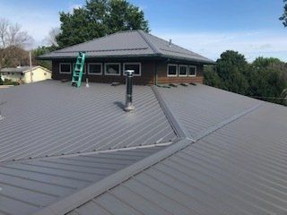 Green Ladder On The Roof — Cedar Valley, IA — Raber Roofing Systems LLC.