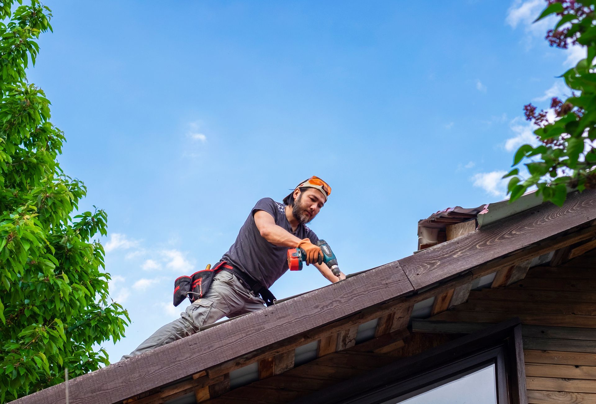Man working on a roof using an electric screwdriver