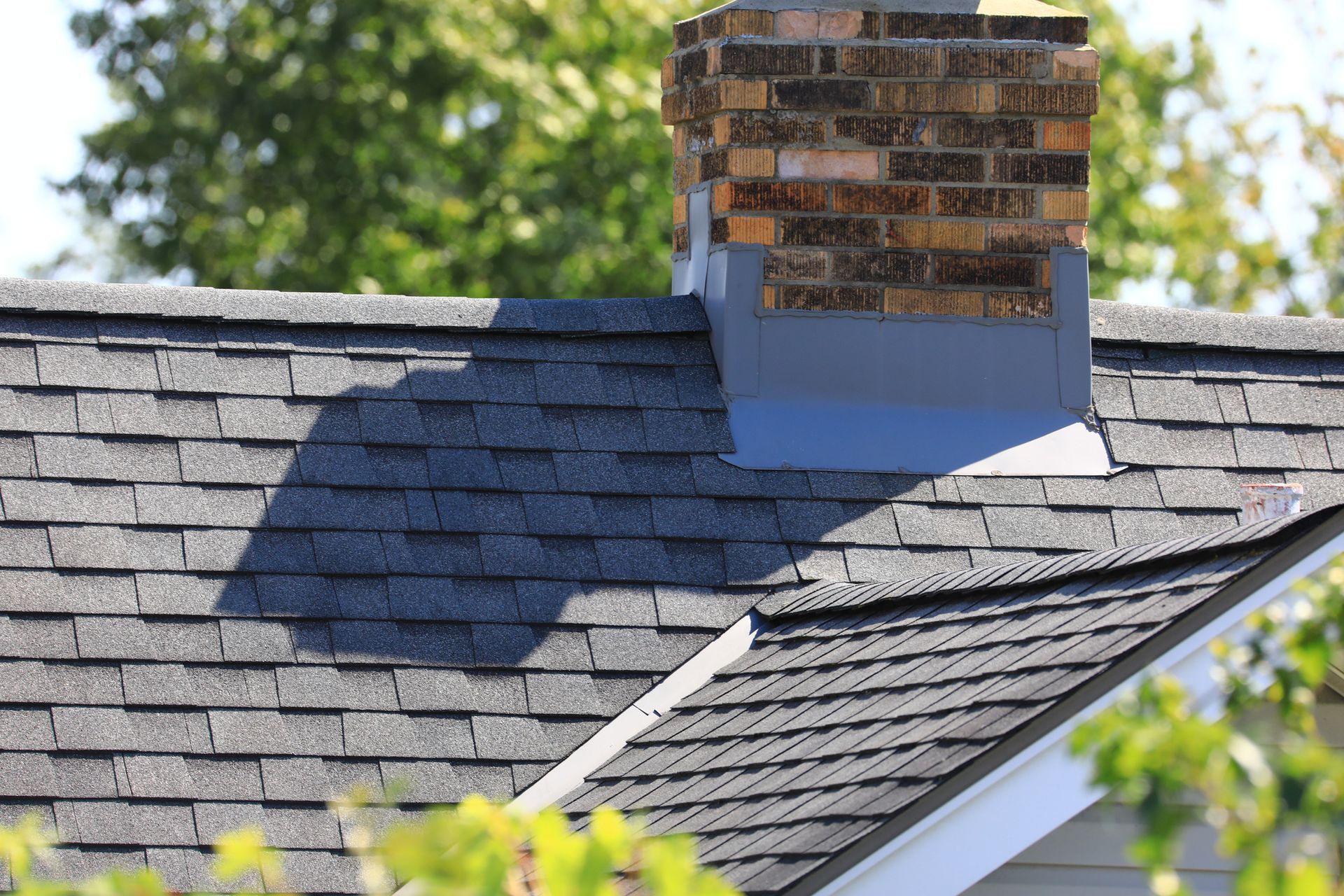 A roof with a gray shingle and chimney