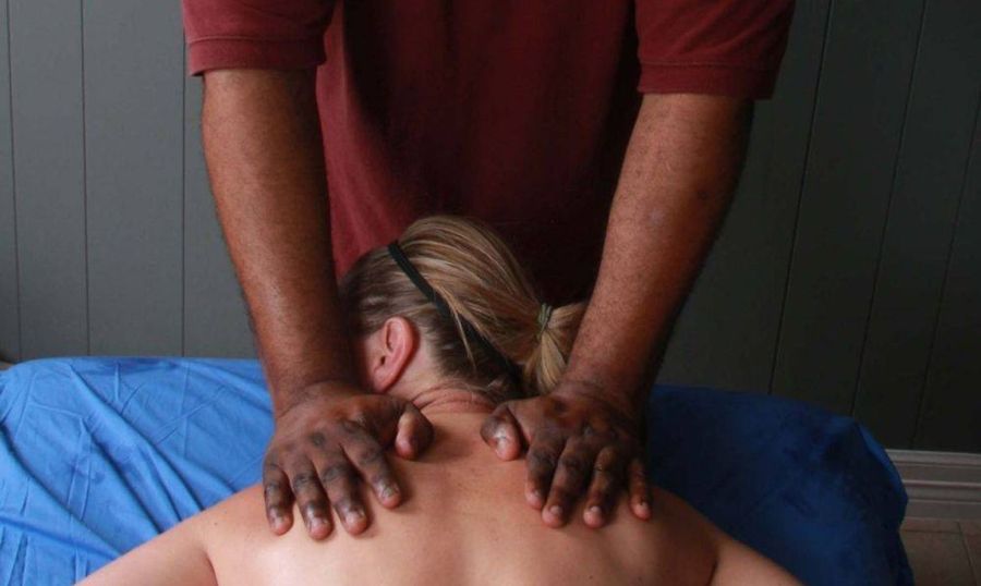 A man is giving a woman a massage on her back