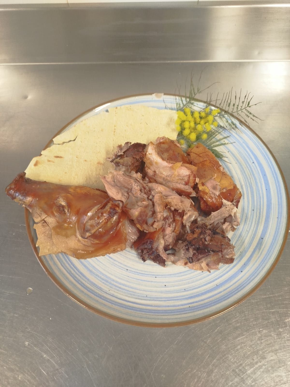 Piatto con carne avanzata e un pezzetto di pane su un bancone in acciaio inox