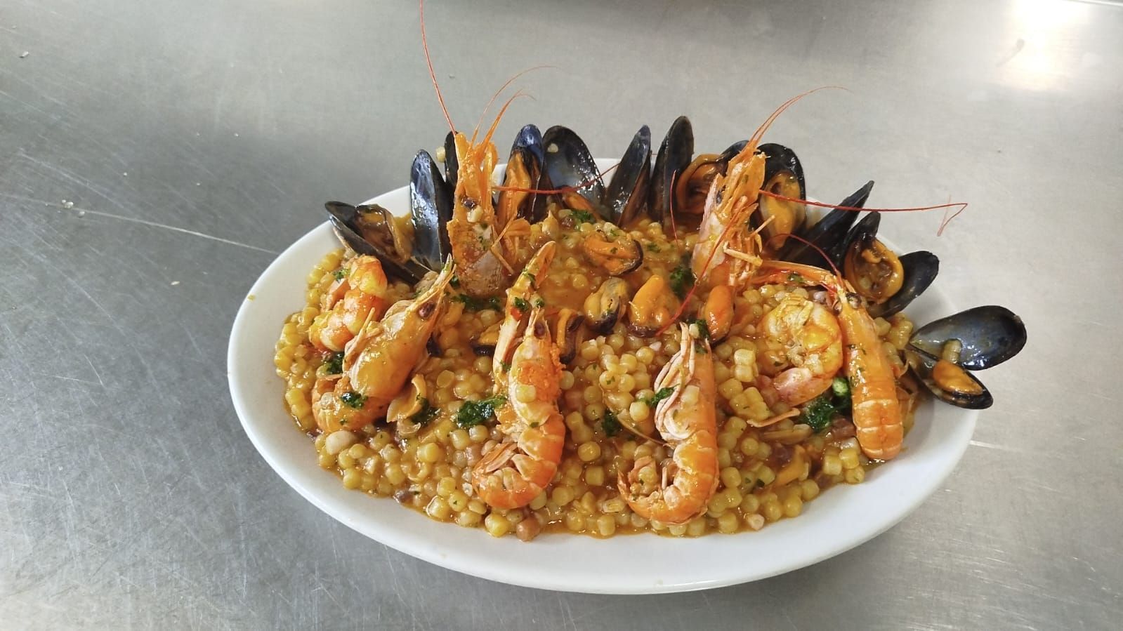Piatto di paella di pesce con gamberi e cozze su un piatto bianco