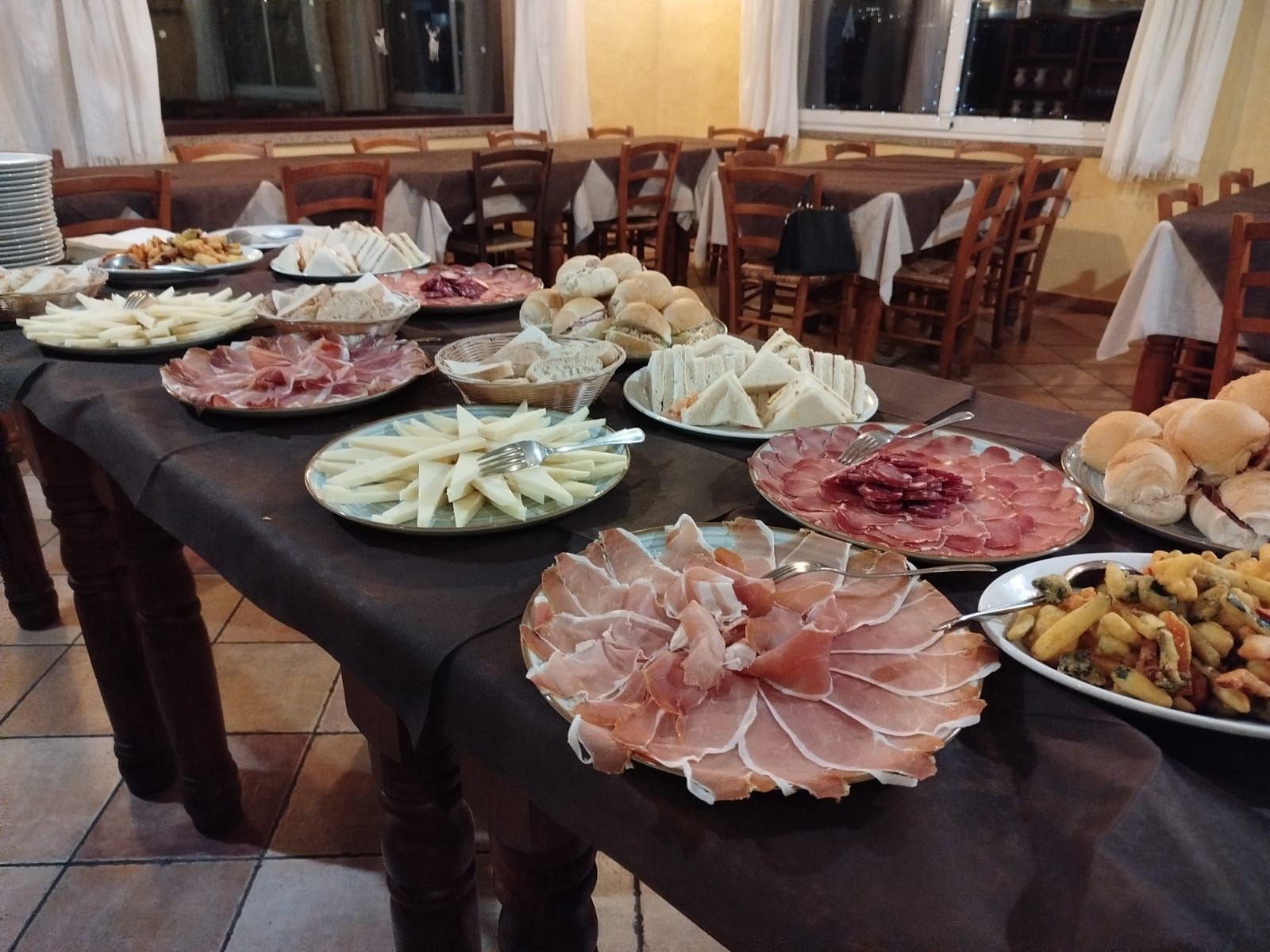 Tavolo da buffet con antipasti assortiti e salumi su una tovaglia nera in una sala da pranzo