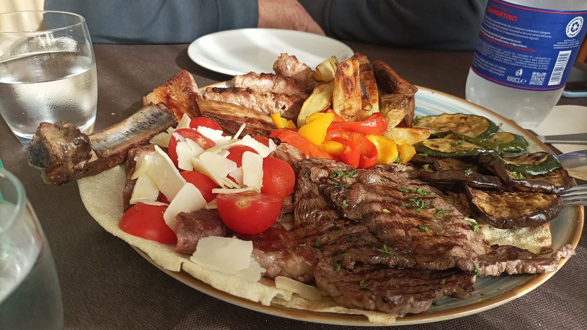 Piatto di carne e verdure grigliate con pomodori e cipolle tritati su un tavolo da pranzo
