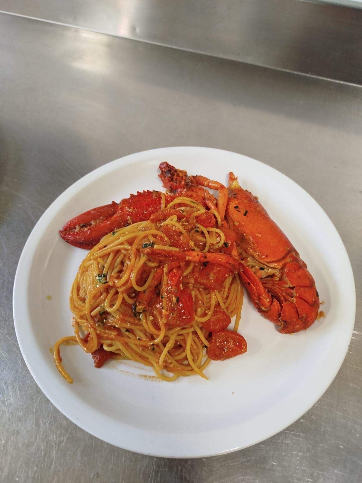 Piatto di spaghetti all'astice in salsa rossa su un piatto bianco.