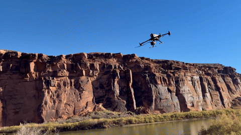 A drone is flying over a mountain with a camera attached to it.