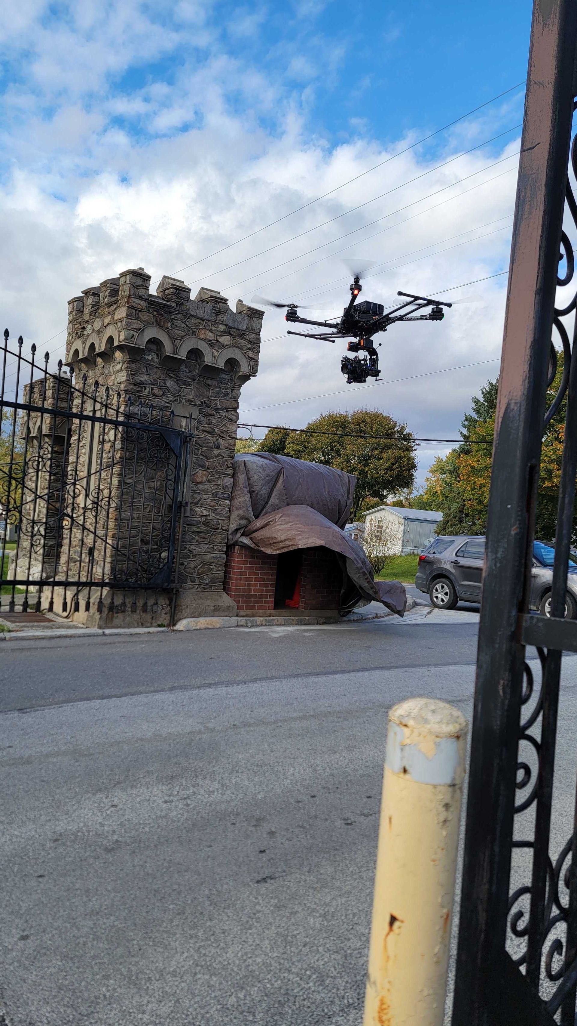 A drone is flying over a gate with a castle in the background.