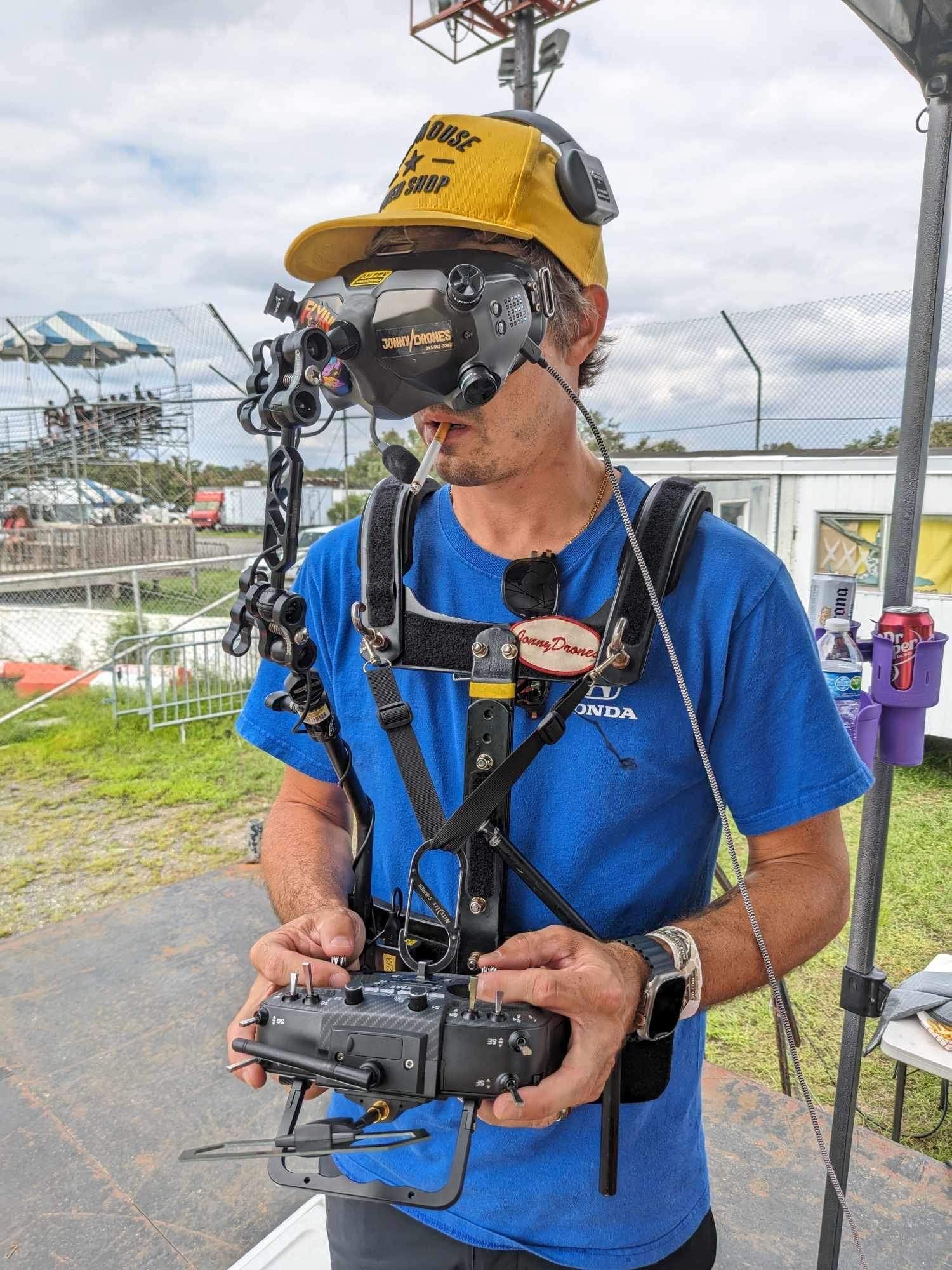 A man wearing a blue shirt and a yellow hat is holding a remote control.