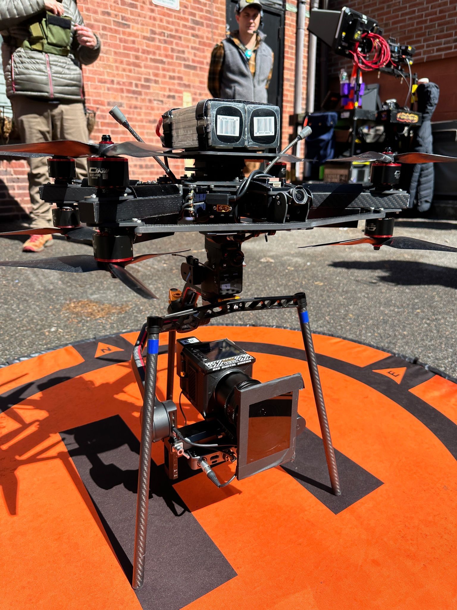 A drone with a camera attached to it sits on an orange mat