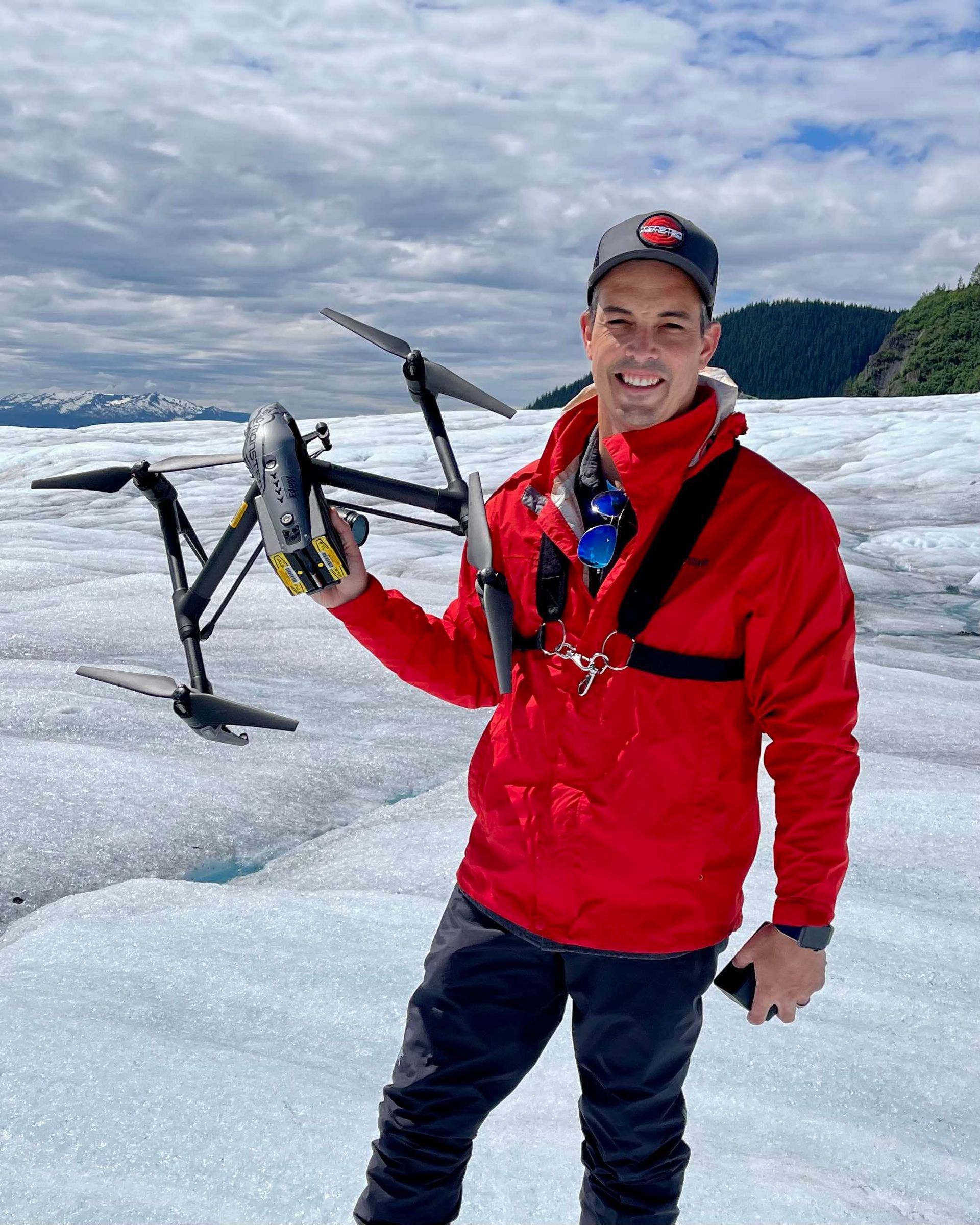 A man in a red jacket is holding a drone in his hand