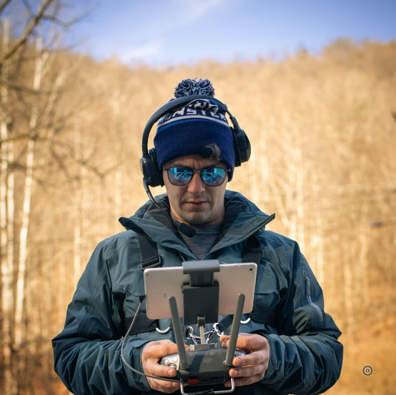 A man wearing headphones and sunglasses is holding a remote control