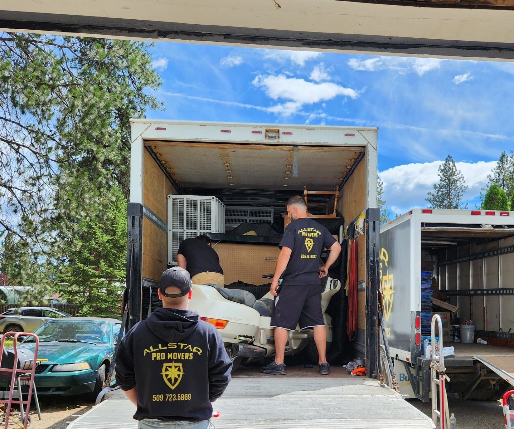Two men are loading a car into a trailer.