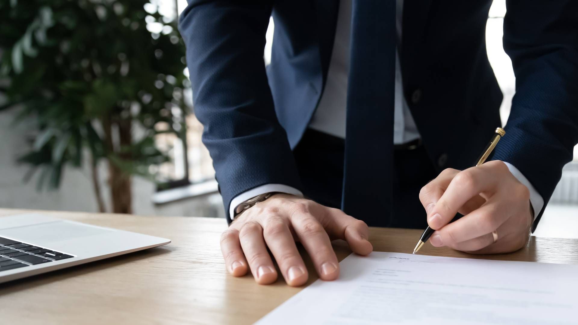 A man in a suit and tie is signing a document.