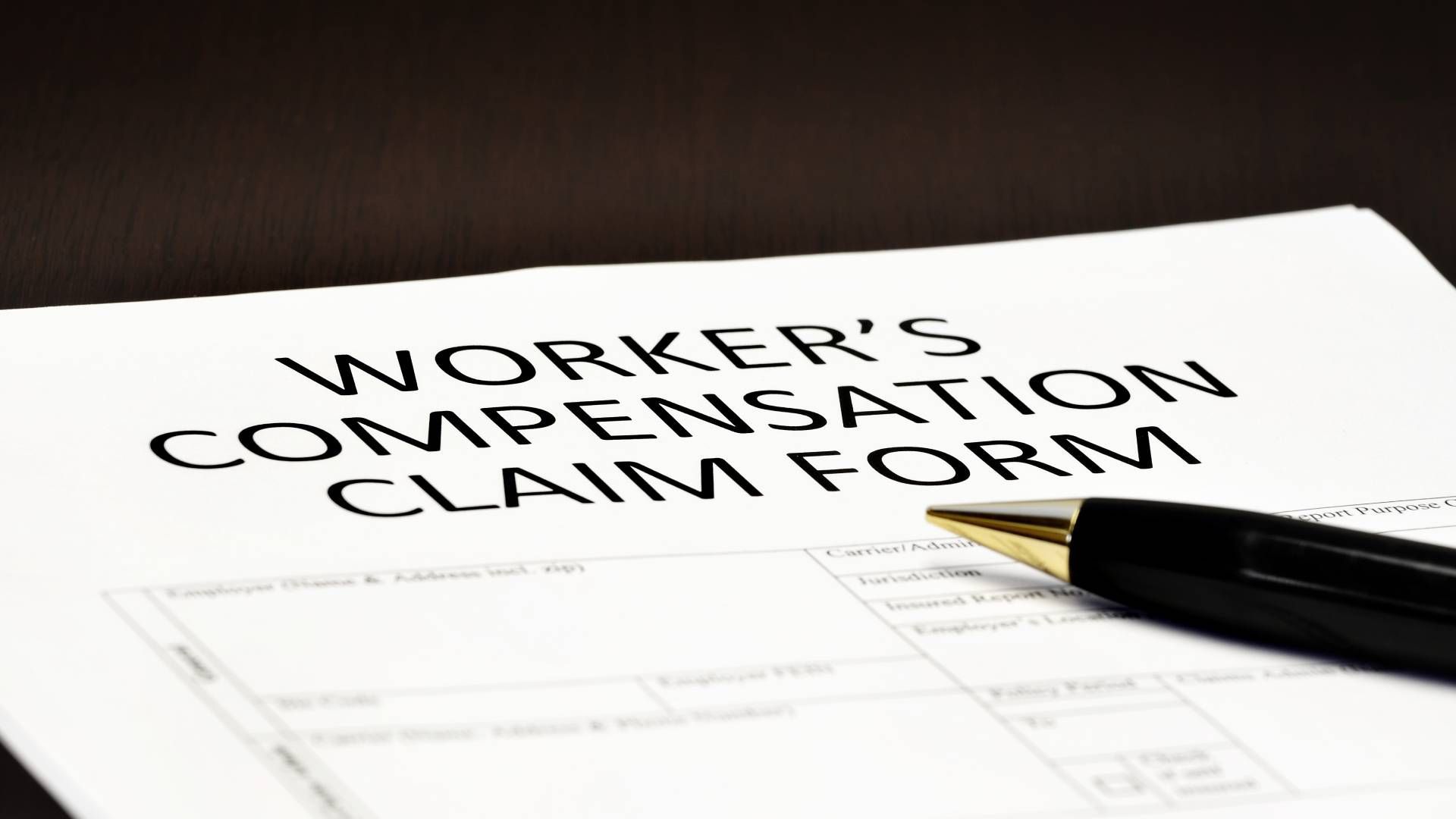 A pen is sitting on top of a worker 's compensation claim form.