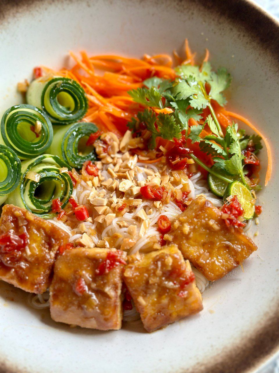 Bowl of Vietnamese noodles with tofu, vegetables, and peanuts.