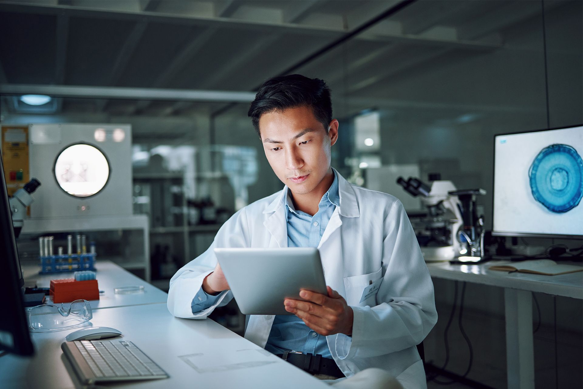 Scientist in a lab coat reviewing a tablet in a modern laboratory