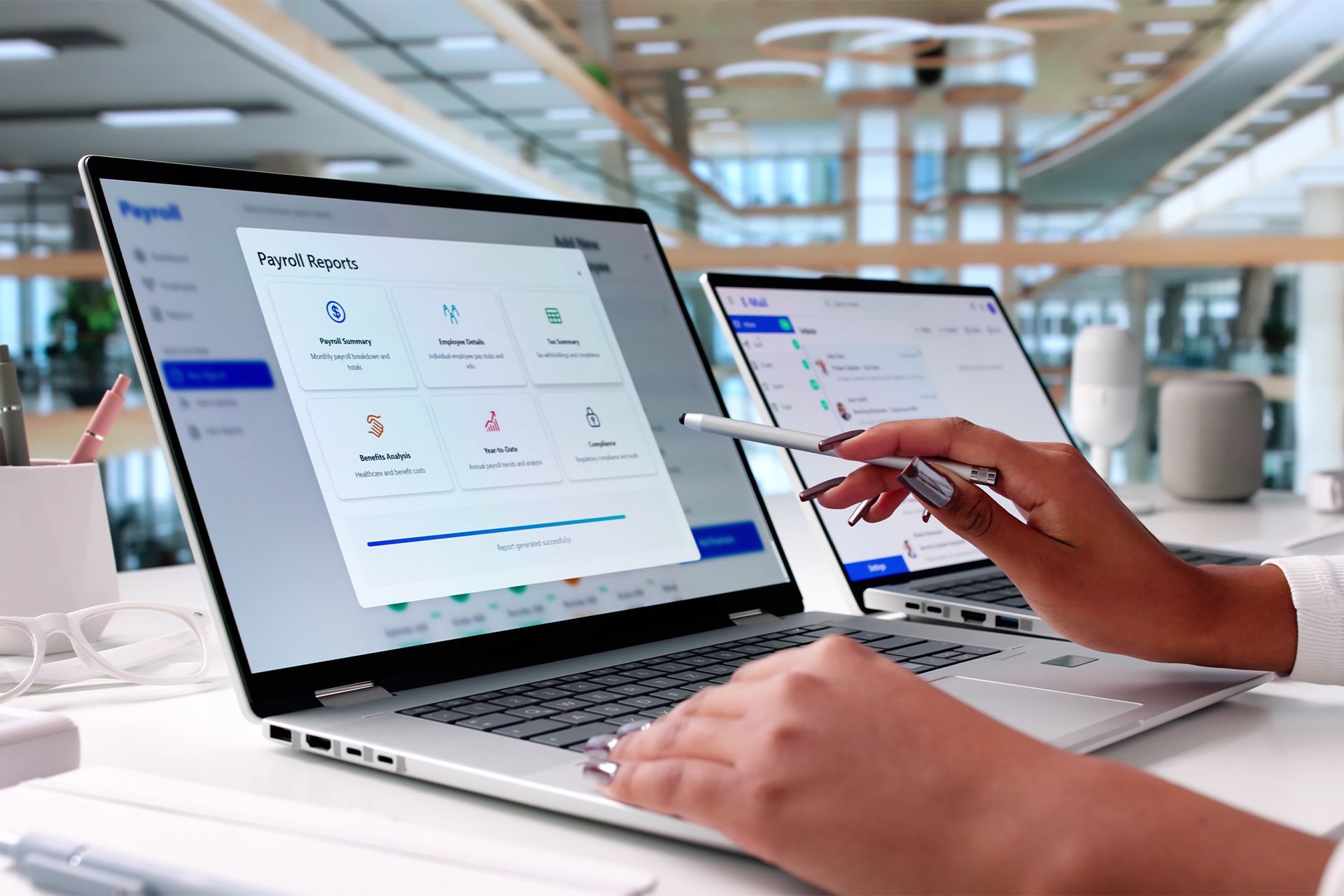 Person using a tablet next to a laptop displaying a dashboard in a bright office