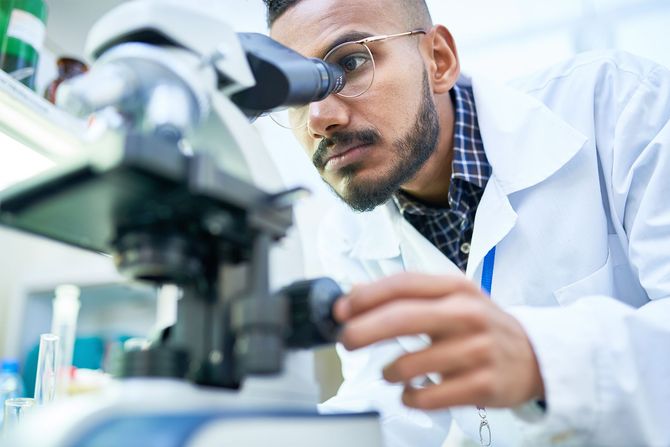 Scientist examining a microscope in a bright laboratory