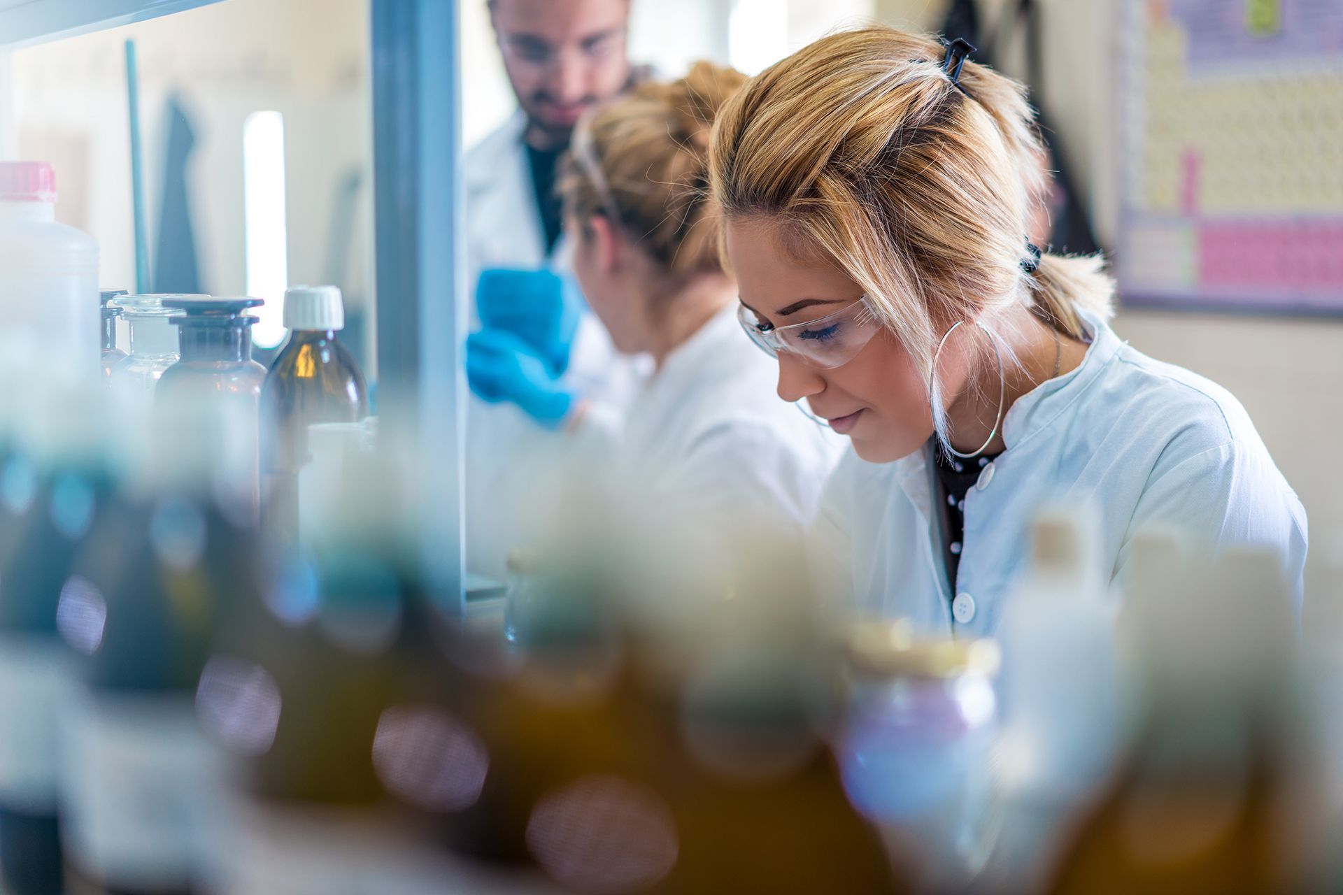 Scientists in lab coats working at a laboratory bench with glassware