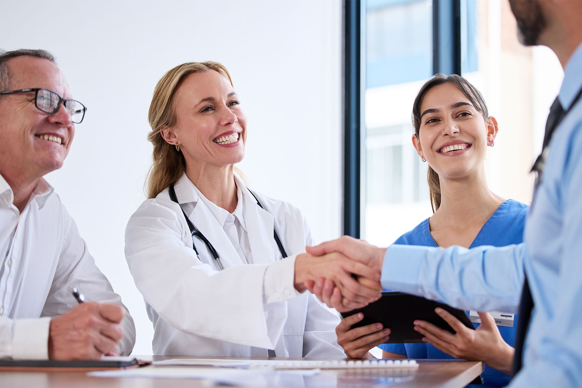 Medical professionals shaking hands in a bright office meeting