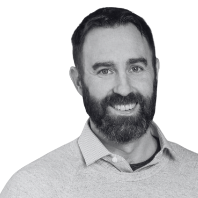 Smiling bearded man in a light collared shirt against a plain background