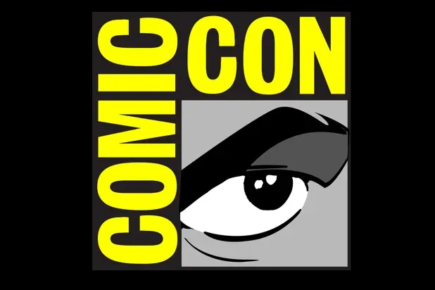 Comic-Con logo with yellow text and a stylized black-and-white eye on a gray background